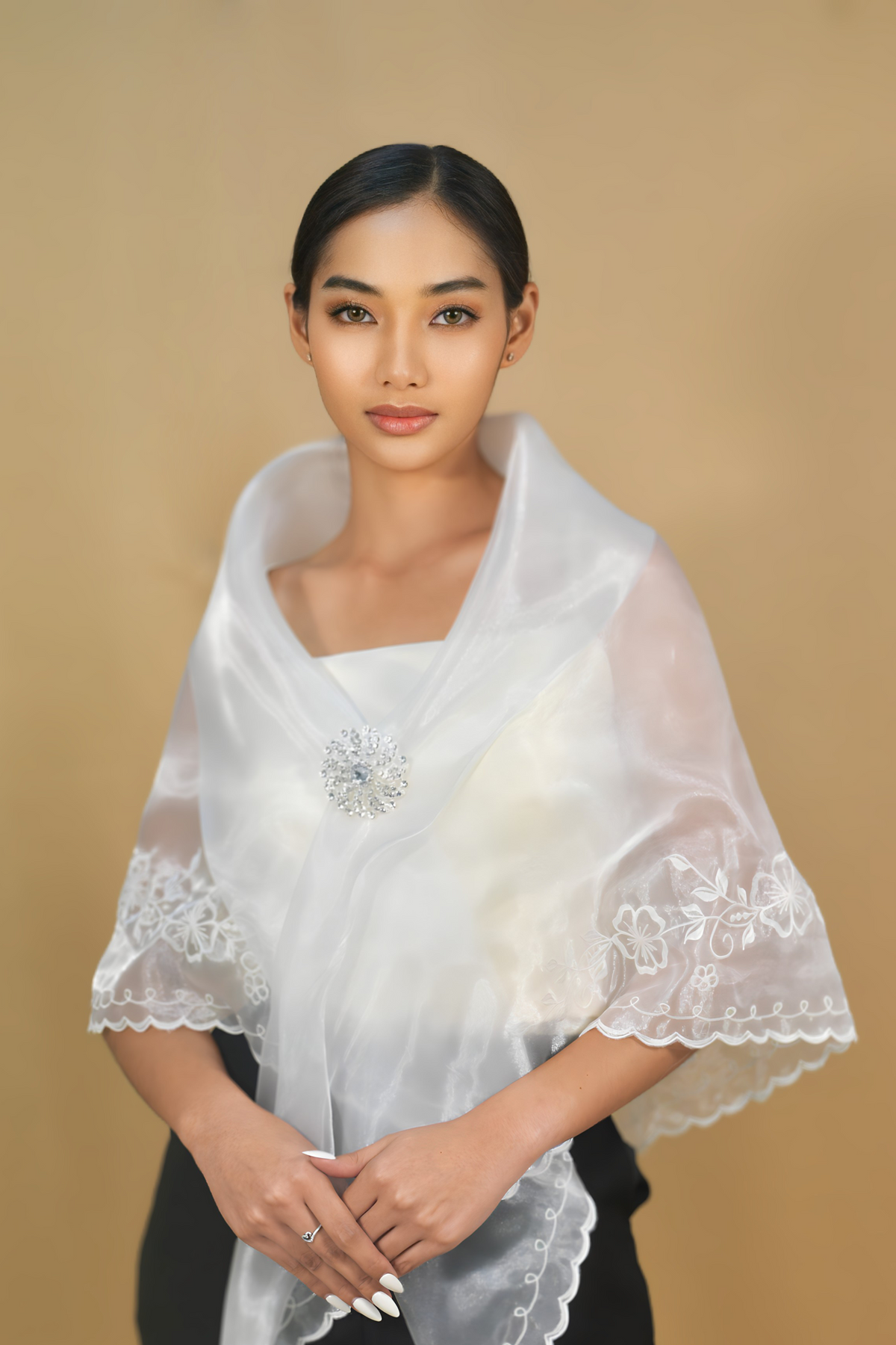 White Filipiniana alampay shawl pinned at the chest with a brooch
