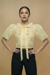 Woman wearing a Beige Filipiniana Kimona blouse with a bow tie against a beige background