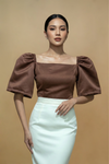Woman wearing a brown Filipiniana Kimona top with puff sleeves and a white skirt 